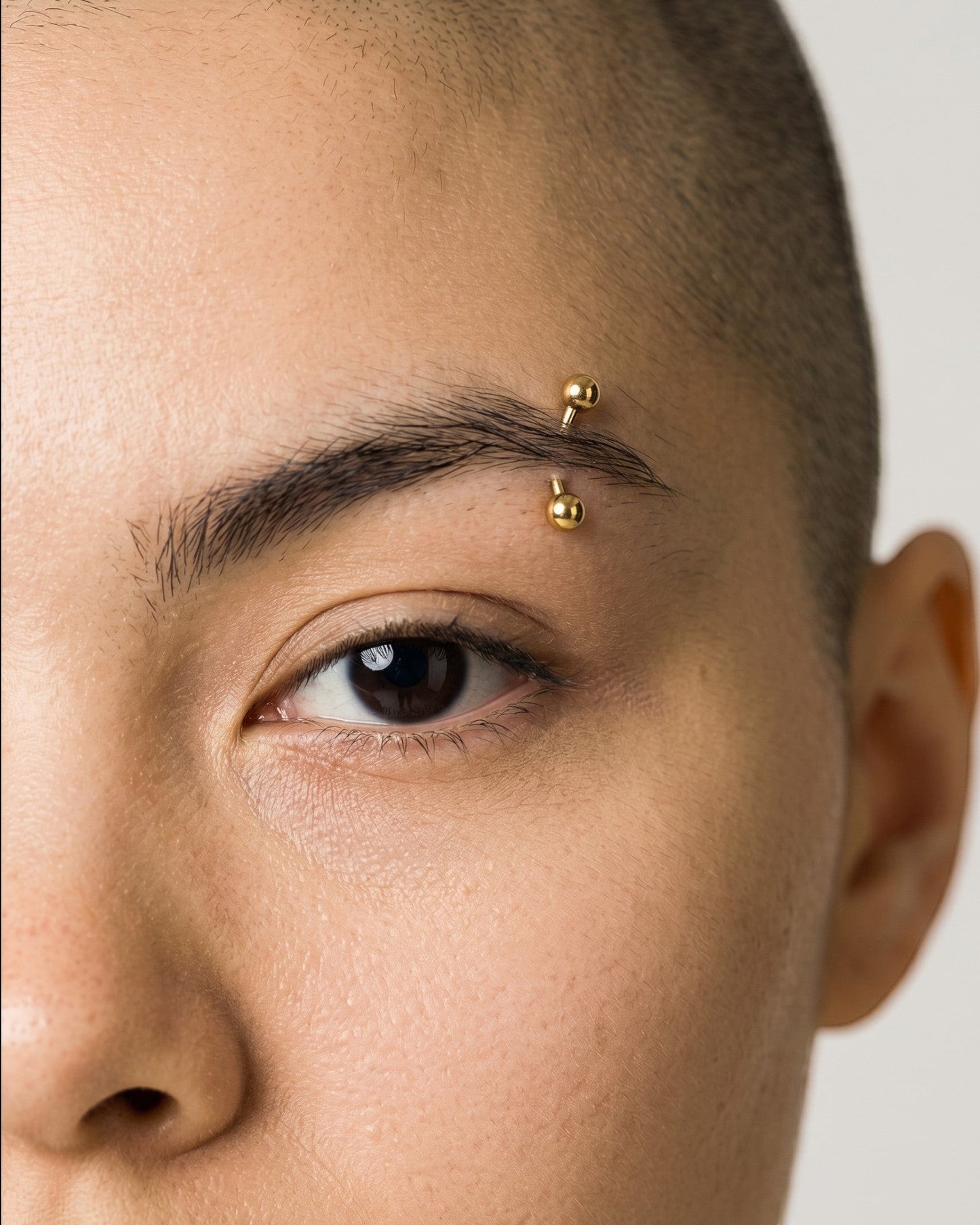 Odonata gold titanium curved banana barbell with screw-on balls for eyebrow piercings, 6mm length, 16G.