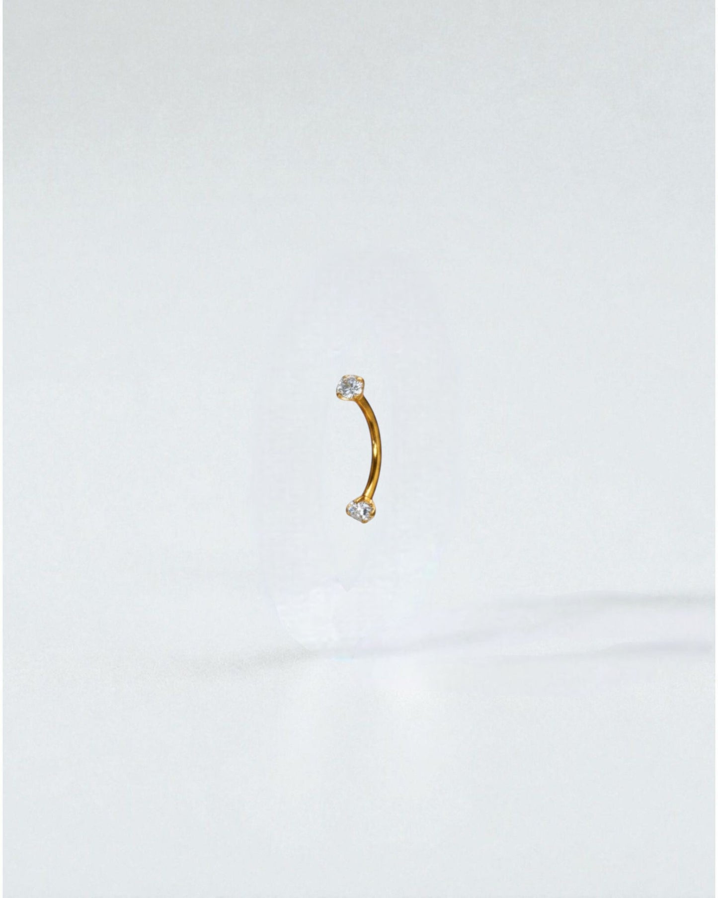 Odonata gold titanium curved barbell with clear cubic zirconia ends, 8mm length, 16G thickness.