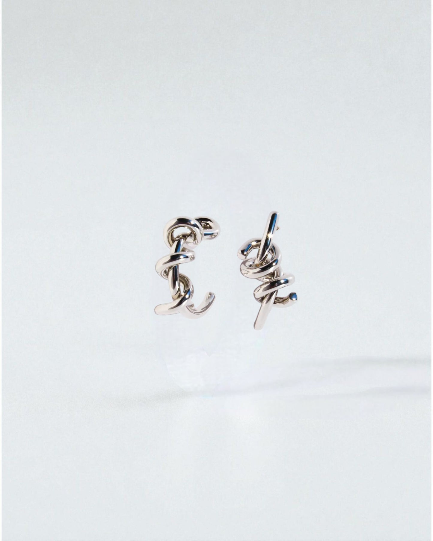 Odonata silver-tone brass twist hoop earrings with 24k gold plating. Modern sculptural design.