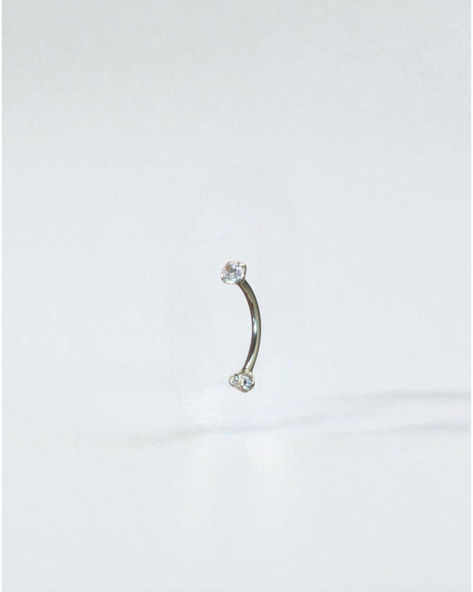 Odonata curved barbell 10mm titanium with two clear cubic zirconia ends, ideal for eyebrow piercings.