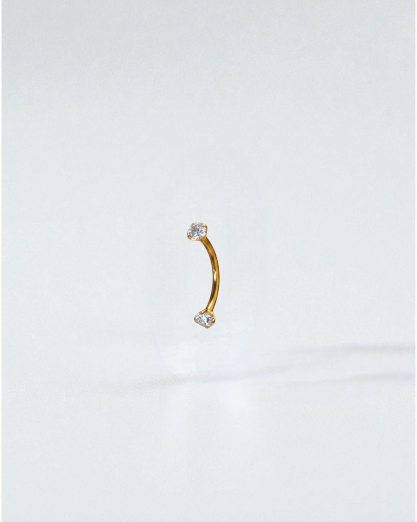 Odonata curved titanium barbell with clear cubic zirconia ends, 10mm length, 16G thickness. Ideal for eyebrow piercings.