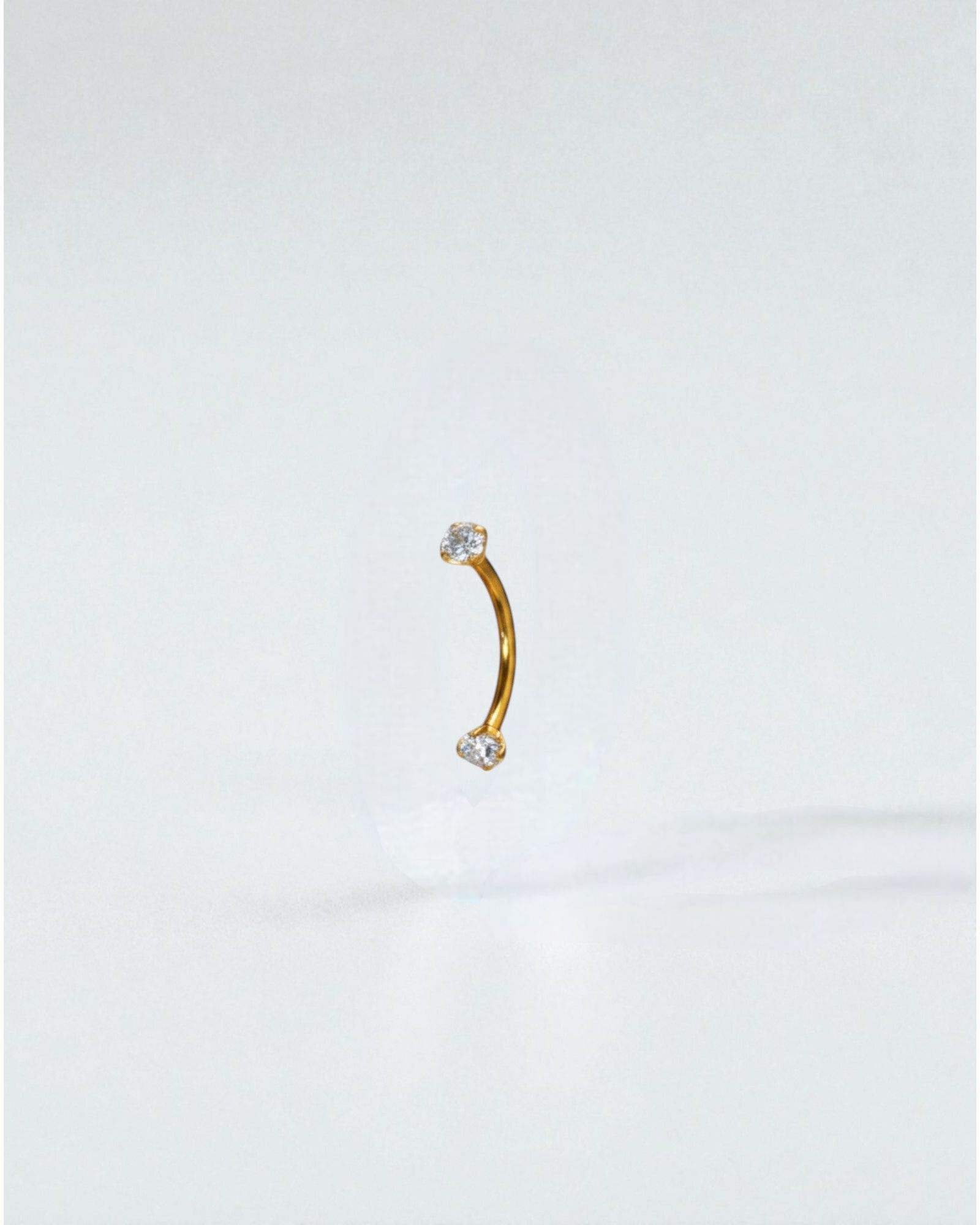 Odonata curved titanium barbell with clear cubic zirconia ends, 10mm length, 16G thickness. Ideal for eyebrow piercings.