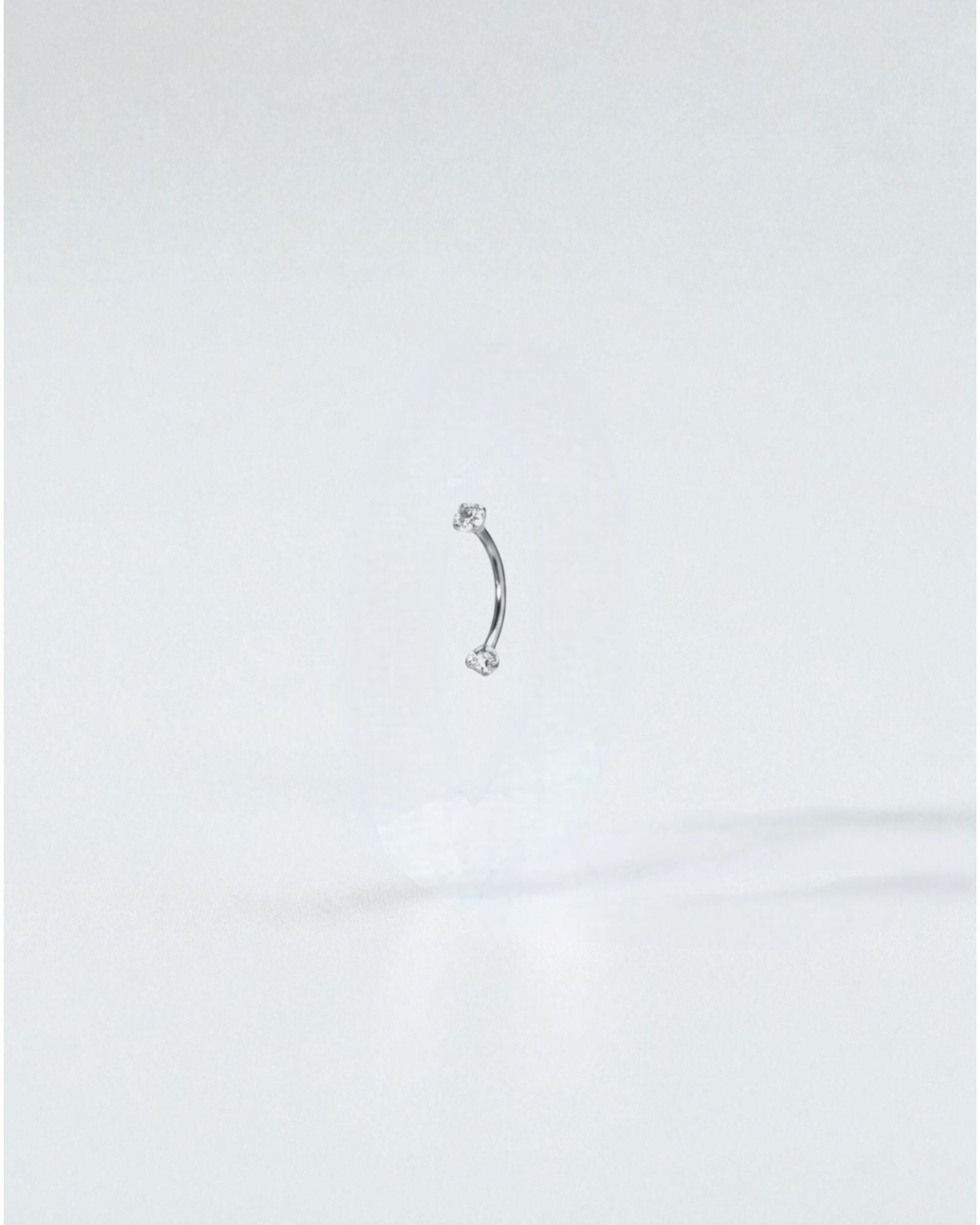 Odonata gold curved barbell with clear cubic zirconia ends, 8mm length, 16G titanium. Ideal for eyebrow piercings.