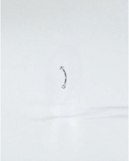 Odonata gold curved barbell with clear cubic zirconia ends, 8mm length, 16G titanium. Ideal for eyebrow piercings.