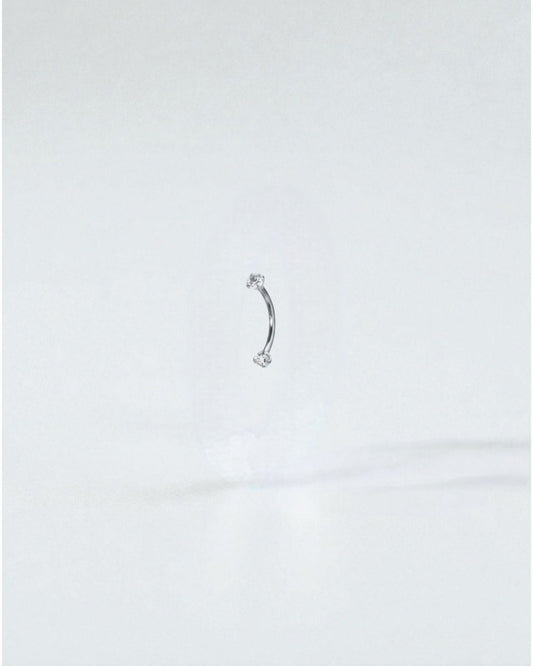 Odonata gold curved barbell with clear cubic zirconia ends, 8mm length, 16G titanium. Ideal for eyebrow piercings.