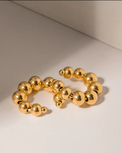 Odonata gold stainless steel hoop earrings with a series of small spheres creating a contemporary, eye-catching design.
