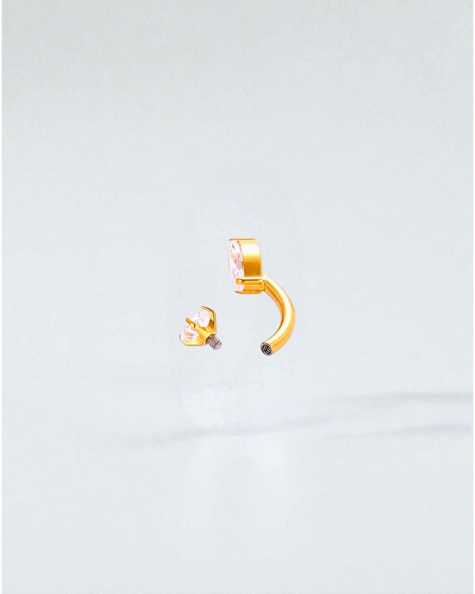 Odonata gold titanium belly button piercing with cubic zirconia drop and round stones. Internal screw closure.