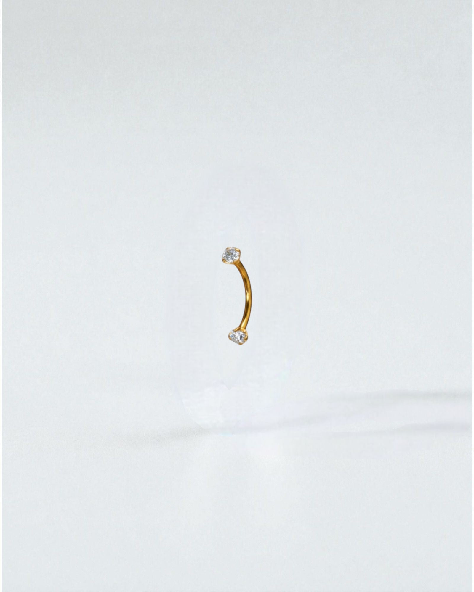 Odonata gold titanium curved barbell with clear cubic zirconia ends, 8mm length, 16G thickness.