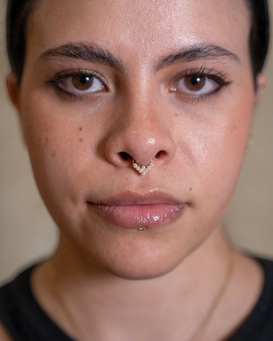 Odonata gold clicker septum piercing with clear zirconias in a V-shape design, made of titanium.