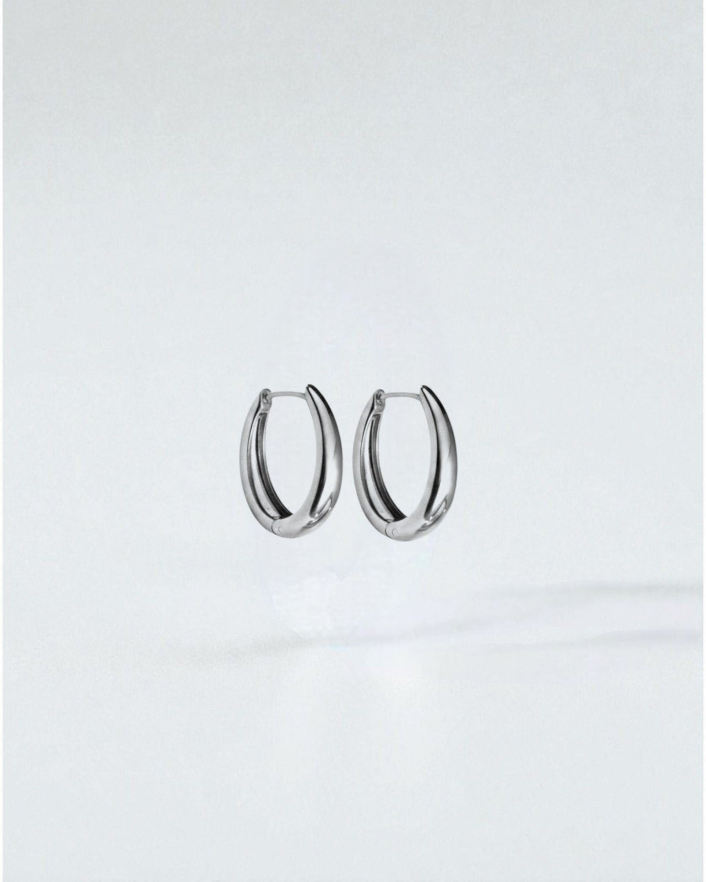 Odonata oval huggie earrings in polished stainless steel with 14k gold plating. Modern, water-resistant design.
