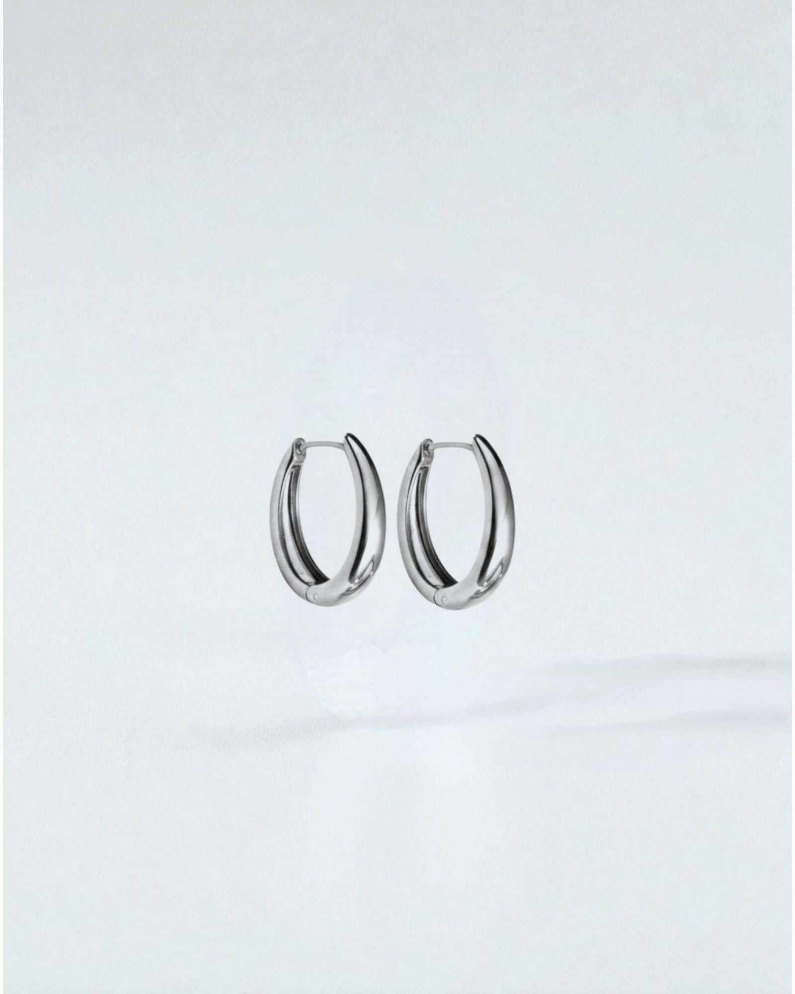 Odonata oval huggie earrings in polished stainless steel with 14k gold plating. Modern, water-resistant design.