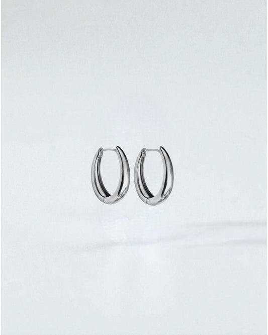 Odonata oval huggie earrings in polished stainless steel with 14k gold plating. Modern, water-resistant design.
