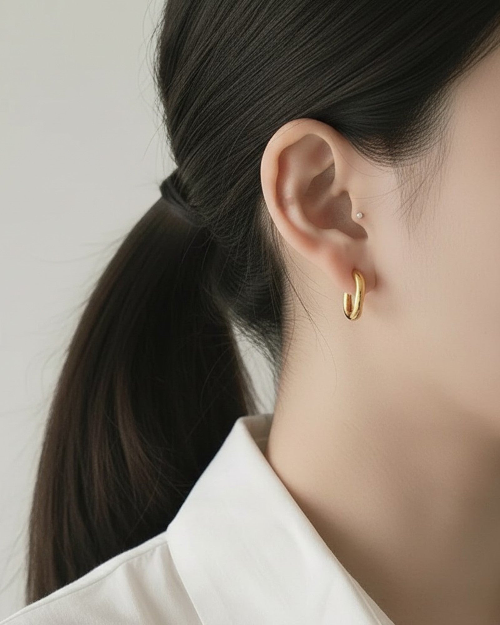 Odonata oval huggie earrings in polished silver-tone stainless steel with 14k gold plating. Modern, timeless design.