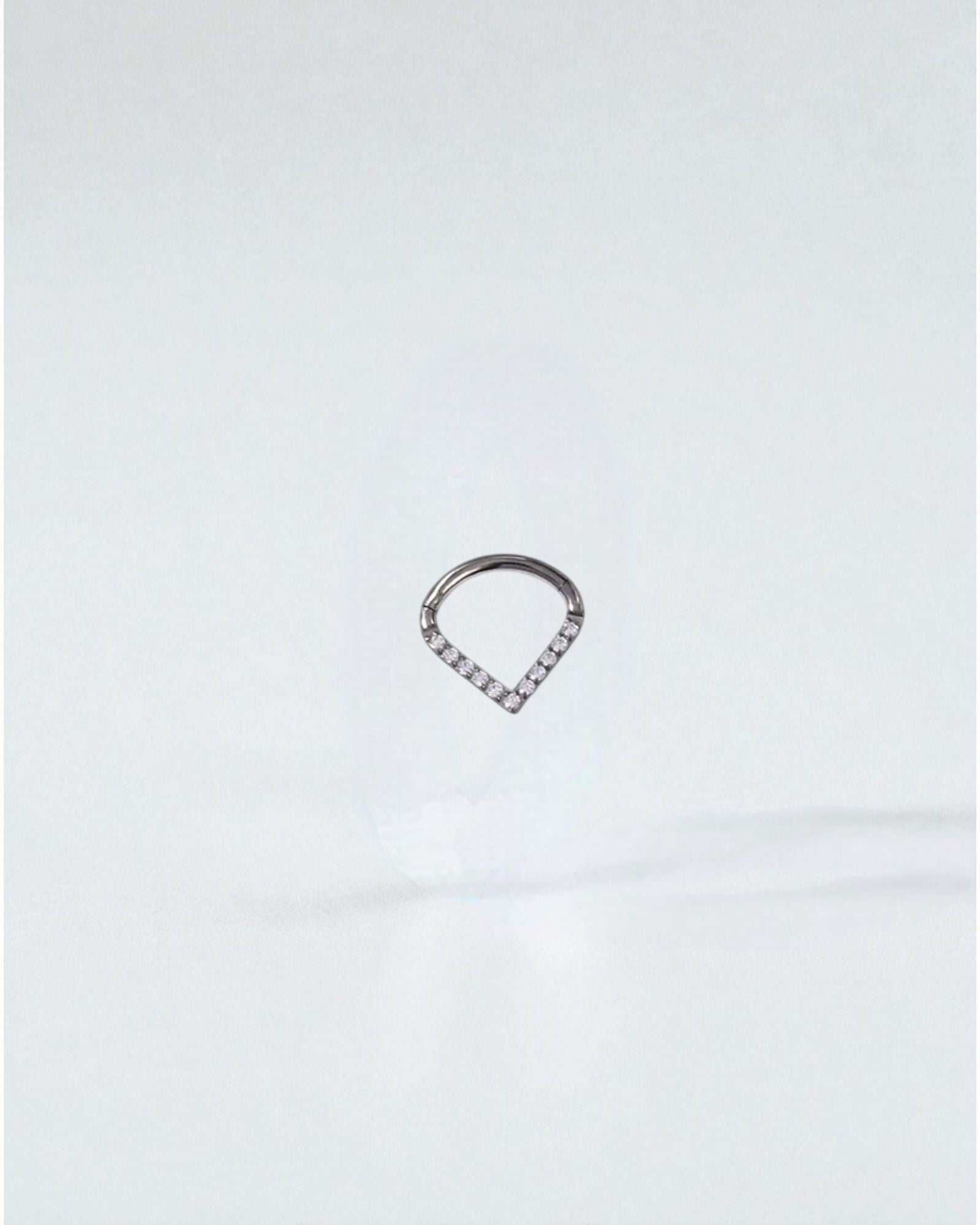 Odonata titanium clicker earring with white cubic zirconia in a V-shape, 8mm diameter, ideal for septum or daith piercings.